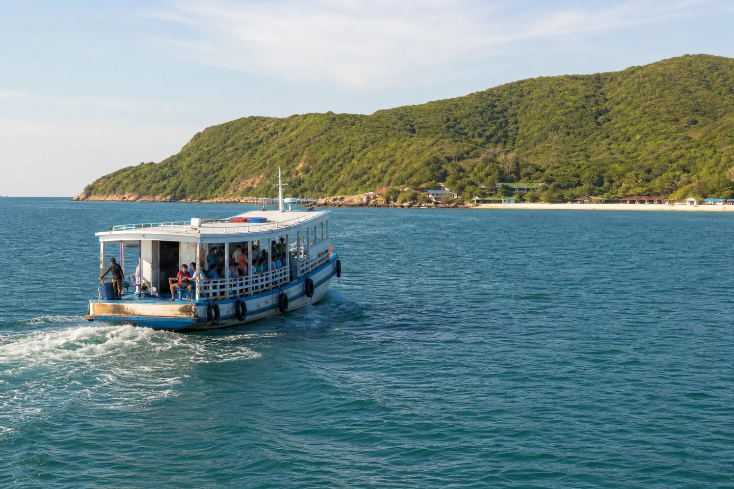 Public passenger ferry approaching the green coastline of Koh Larn